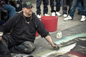 Chalkmaster Dave sitting on sidewalk drawing