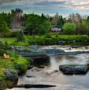 Adirondack chairs by babbling brook with cottage