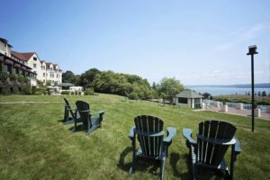 Adirondack chairs outside of large hotel overlooking water