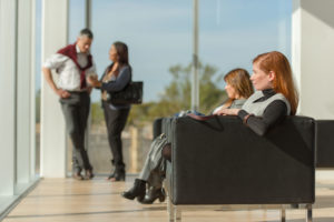 Inside of office building with people standing chatting and others seated