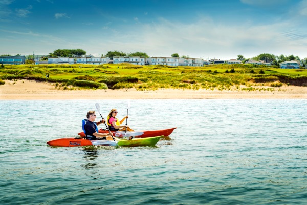 Two kayakers paddling in front of Cabot Links